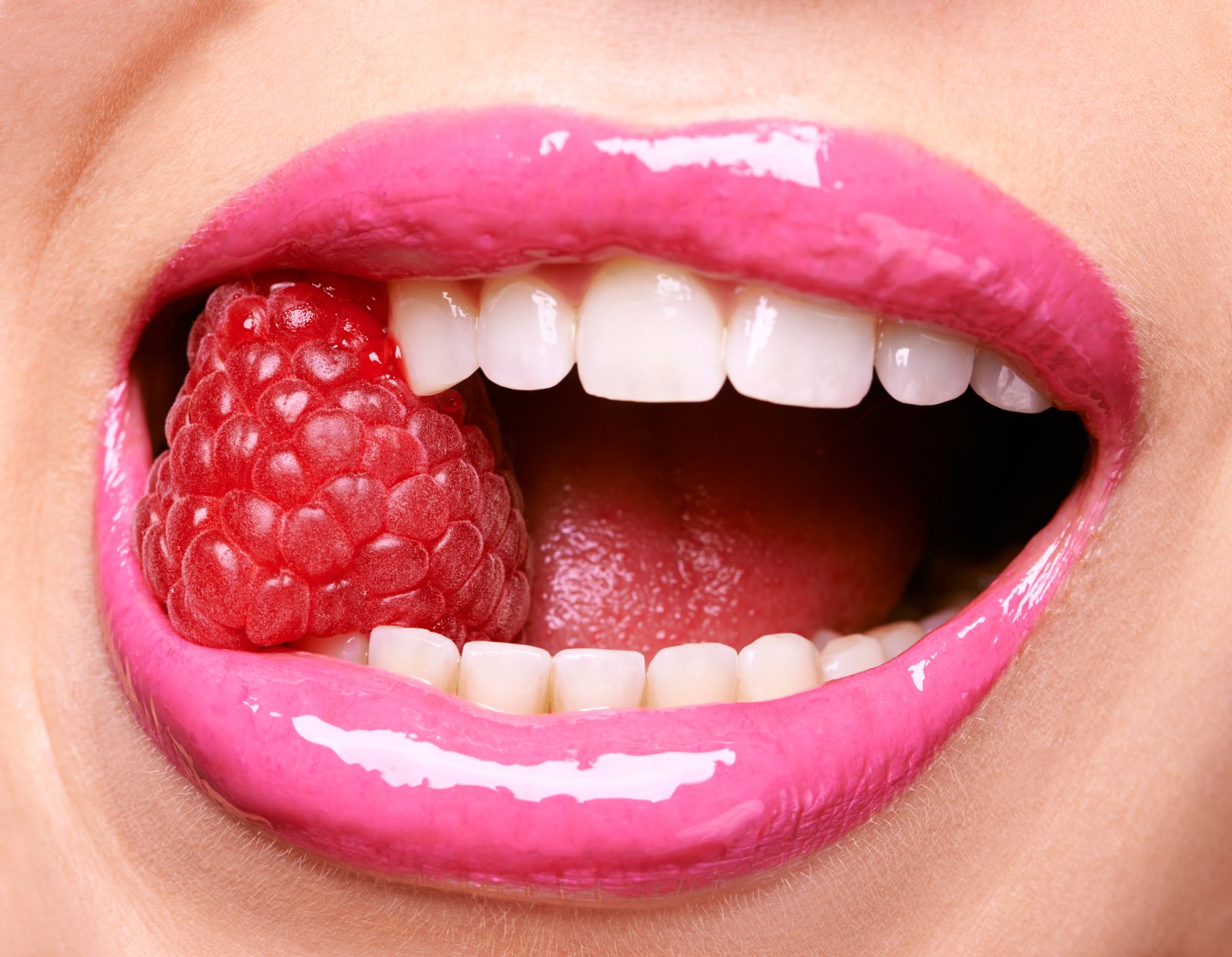 woman with white teeth eating raspberry